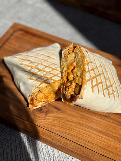 Grilled French taco cut in half on a wooden board