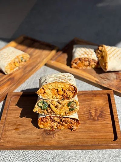 Grilled French tacos stacked on a wooden board