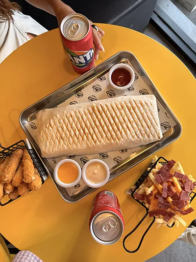 French tacos, chicken tenders, fries and dipping sauces on a tray