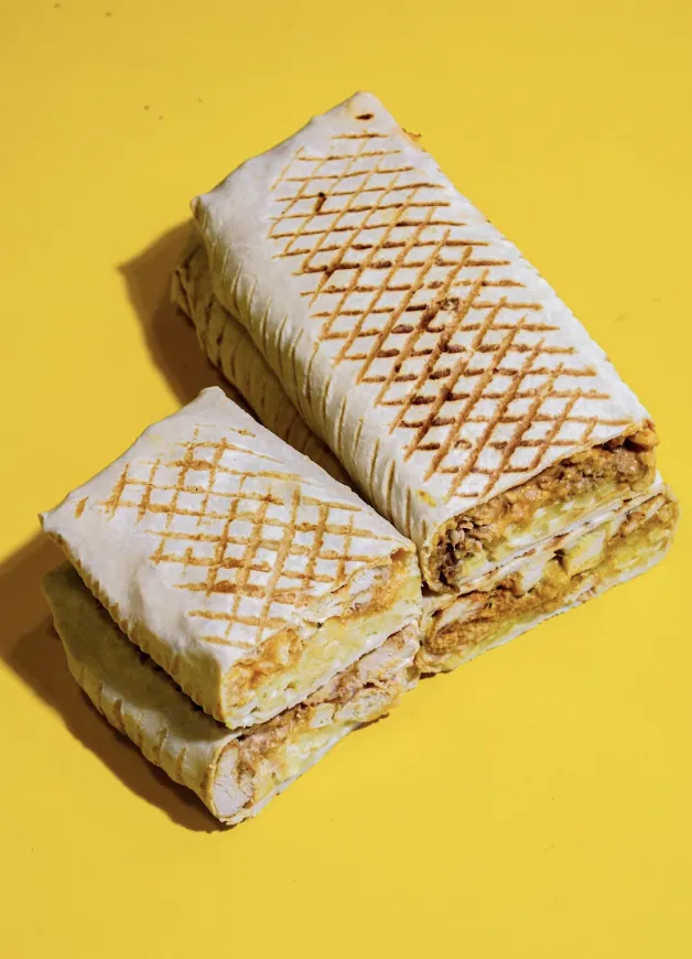 Grilled French tacos cut in half on a yellow table